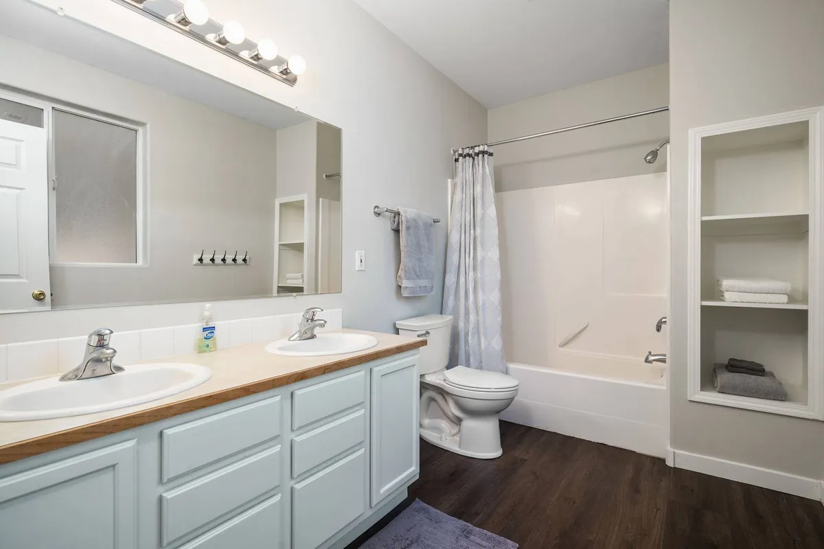 A spa-inspired bathroom with a double sink vanity, expansive mirror, and a soothing bathtub, bathed in soft natural light. The space exudes freshness and tranquility, inviting guests to unwind after a day of adventure.