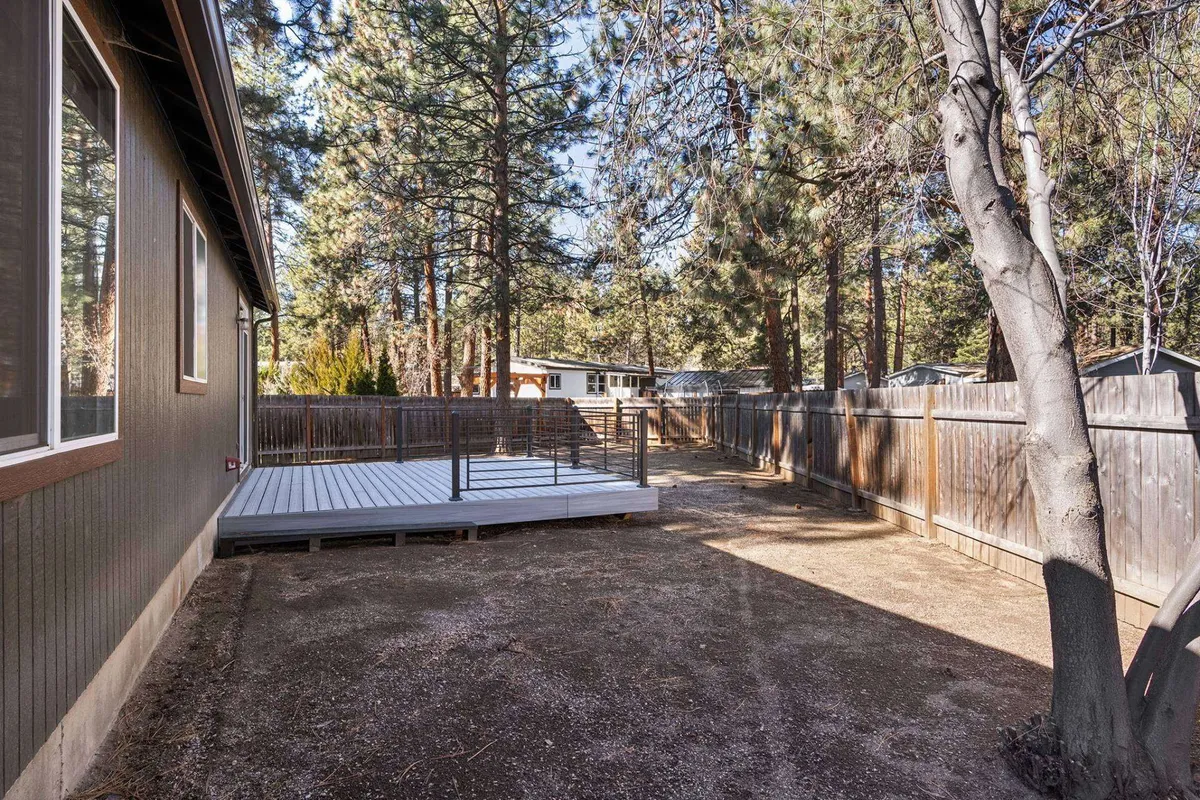 A peaceful deck scene with a sturdy fence and tall trees beyond, perfect for outdoor dining or stargazing. The setup allows for grilling, socializing, or unwinding while being immersed in nature.