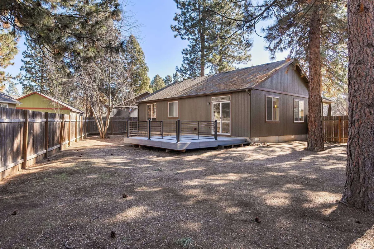 A spacious deck overlooking a fenced backyard with mature trees, ideal for outdoor gatherings, barbecues, and relaxation after a day of exploration.